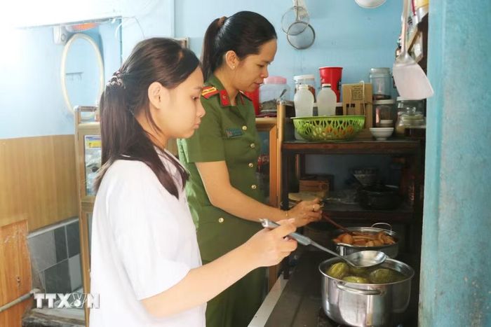 Em Trần Nguyễn Mai Thảo (phường Trảng Bom, thành phố Đồng Nai) cùng với mẹ nuôi là Công an chuẩn bị bữa cơm gia đình. (Ảnh: Lê Xuân/TTXVN)