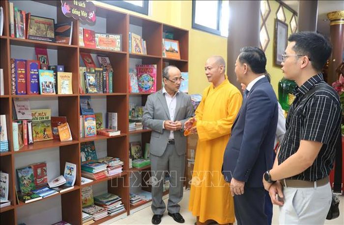 Trụ trì Chùa Phật Tích thủ đô Viêng Chăn giới thiệu về tủ sách. Ảnh: Xuân Tú/PV TTXVN tại Lào