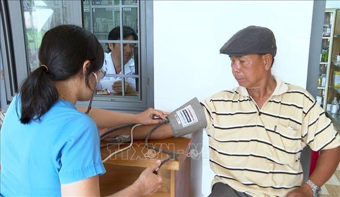 Nhân viên y tế đo huyết áp cho người dân đến khám tại Trạm Y tế xã Lộc Quang.