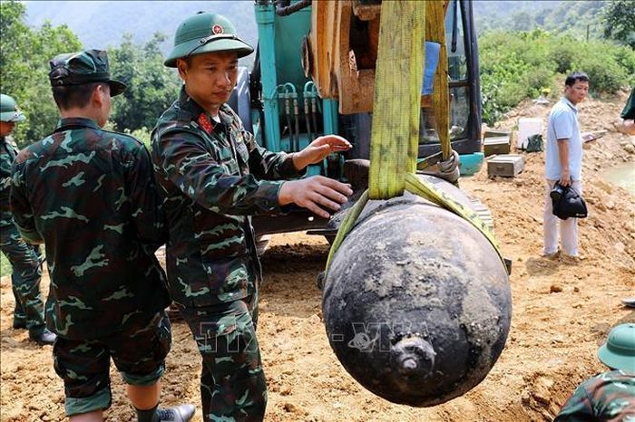 Lực lượng chức năng cẩn trọng di dời bom xuống hố hủy nổ.