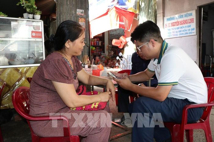 Tạo tài khoản ngân hàng cho tiểu thương chợ Nhị Long phục vụ việc thanh toán không dùng tiền mặt. Ảnh: Thanh Hòa- TTXVN