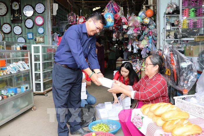 Trao thiết bị hỗ trợ tiểu thương chợ Nhị Long dùng phương thức thanh toán không dùng tiền mặt. Ảnh: Thanh Hòa- TTXVN