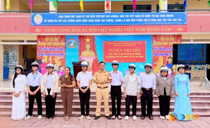 Cô Phạm Thị Thứ, Hiệu trưởng nhà trường và Trung tá Phan Văn Quang tặng mũ bảo hiểm cho giáo viên, học sinh. Ảnh: CÔNG TÚ