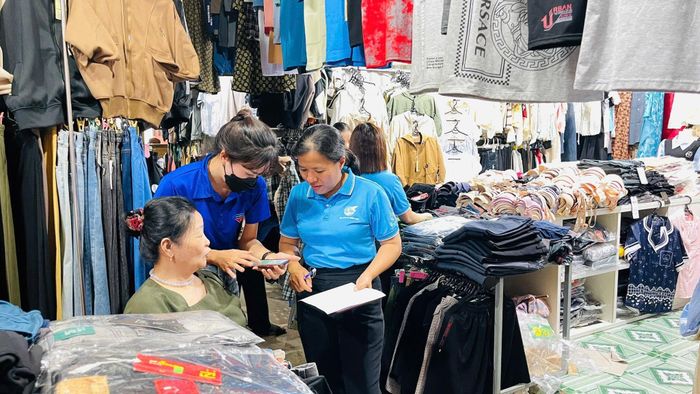 Các thành viên tổ công nghệ số cộng đồng và lực lượng đoàn viên, thanh niên trực tiếp hướng dẫn các hộ kinh doanh tiếp cận, cài đặt và sử dụng những tiện ích số tại chợ Cát Tiên