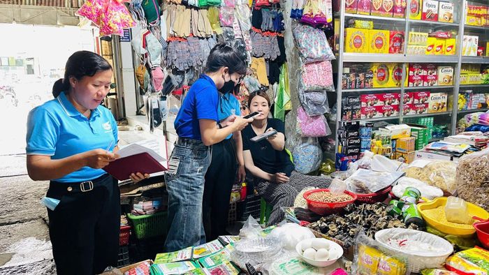 Các thành viên tổ công nghệ số cộng đồng và lực lượng đoàn viên, thanh niên trực tiếp hướng dẫn các hộ kinh doanh tiếp cận, cài đặt và sử dụng những tiện ích số tại chợ Cát Tiên