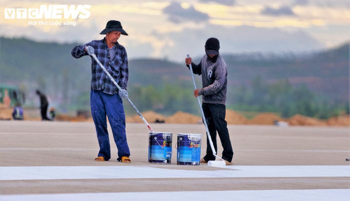 Giữa mặt đường băng bê tông số 2 dài hơn 3.000m , từng tốp công nhân lưng áo ướt đẫm mồ hôi, người cặm cụi sơn vạch đường băng, phay từng đường rãnh kháng trượt, tỉ mỉ kéo cáp, đấu nối từng cụm đèn hiệu hàng không.