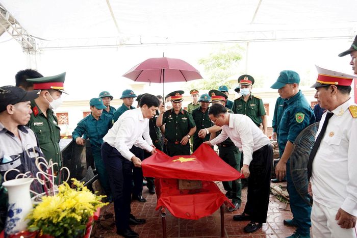 Lãnh đạo phường Chương Mỹ thực hiện nghi thức phủ Quốc kỳ trong quá trình đưa hài cốt liệt sĩ đến khu vực lấy mẫu. Ảnh: Lan Oanh 