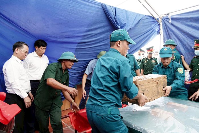 Các lực lượng làm nhiệm vụ cẩn trọng từng thao tác đưa tiểu quách liệt sĩ ra khỏi phần mộ. Ảnh: Lan Oanh