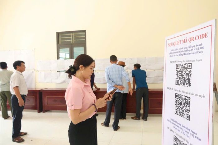 Người dân đóng góp ý kiến trực tuyến thông qua mã QR tại điểm niêm yết Nhà văn hóa thôn Đông Cao. Ảnh: PV