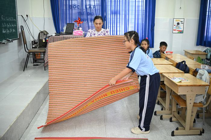 Cô Kiều Thị Thu Hà, giáo viên chủ nhiệm lớp 4/1, cho biết ban đầu, nhà trường dự kiến để phụ huynh đón học sinh về vào buổi trưa. Tuy nhiên, một số gia đình ở xa cho biết nếu phải đưa đón con giữa buổi thì có thể cho con nghỉ luôn buổi chiều. Lo các em mất tiết học, cô Hà đề xuất với hiệu trưởng để mình ở lại trường trông học sinh, còn phụ huynh chuẩn bị thức ăn cho con.