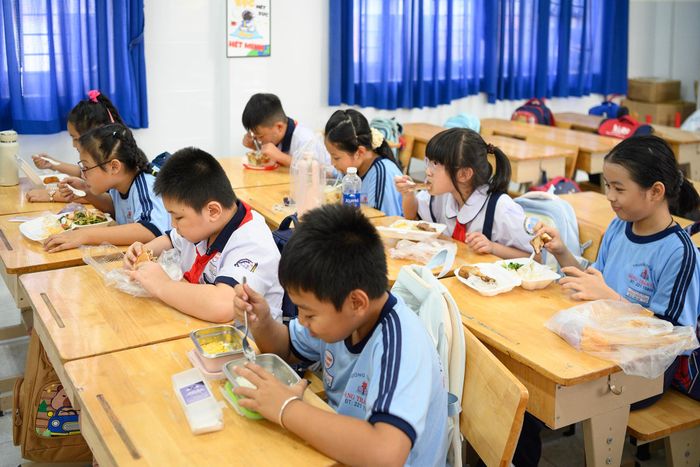 Đối với học sinh ở xa hoặc phụ huynh không thể về đón con vào buổi trưa, nhà trường phân công giáo viên ở lại hỗ trợ. Phụ huynh chuẩn bị thức ăn và gửi đến trường, giáo viên cho học sinh ăn, nghỉ ngơi và ngủ tại lớp trước khi các em tiếp tục học buổi chiều. Theo bà Hà, đây là phương án nhằm hỗ trợ những gia đình gặp khó khăn trong việc đưa đón con nhiều lần trong ngày.