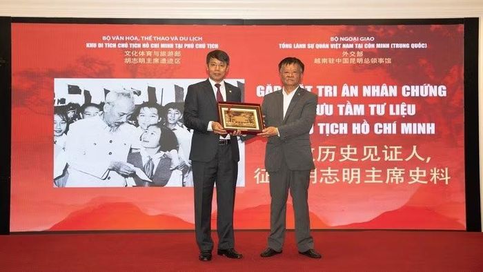 Ông Nguyễn Văn Dương, Phó Giám đốc Khu Di tích Chủ tịch Hồ Chí Minh tại Phủ Chủ tịch trao tặng Phù điêu Nhà sàn Bác Hồ cho ông Phạm Gia Đức, Chủ tịch Hội người Việt tại Vân Nam. (Ảnh: BAN TỔ CHỨC)