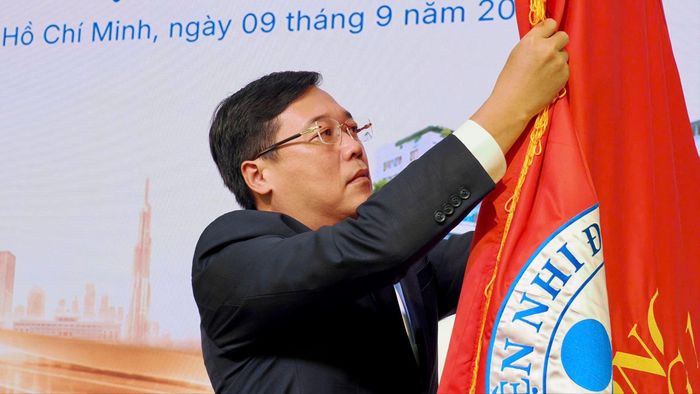 Phó Bí thư Thường trực Thành ủy TPHCM Lê Quốc Phong gắn Danh hiệu Anh hùng Lao động lên cờ truyền thống Bệnh viện Nhi đồng 1 (Ảnh: HOÀNG HÙNG)