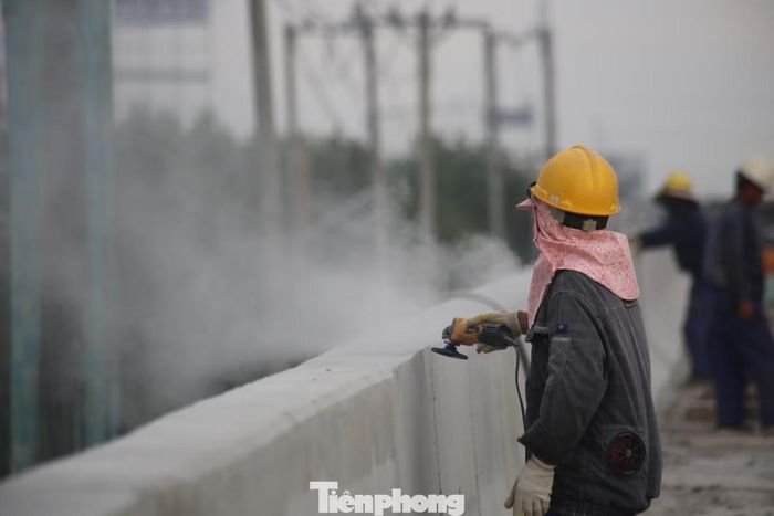Tại một đoạn công trường, các công nhân gần như không có thời gian ngơi tay. Người điều khiển máy, người xử lý mặt đường, người lắp đặt các hạng mục phụ trợ. Mỗi công nhân một phần việc, tất cả cùng hướng tới một mốc thời gian chung: đưa dự án về đích cuối năm 2026.