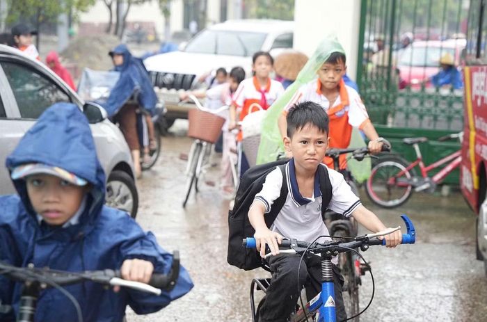 Một số học sinh đầu trần đội mưa tự đi xe đạp về nhà