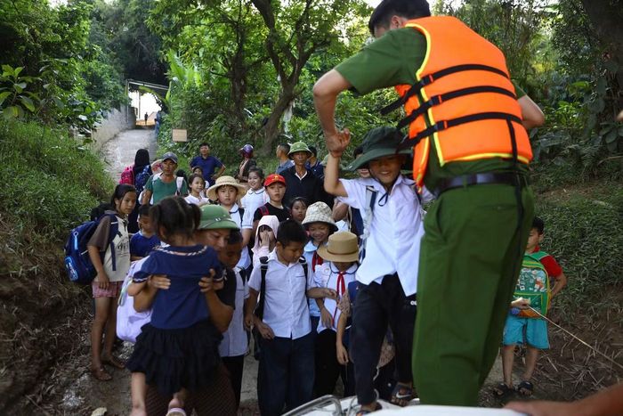 Người dân, học sinh lên cano của Phòng CSGT để qua sông đến lớp