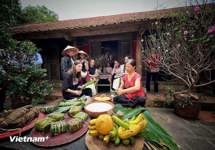 Du khách quốc tế trải nghiệm làm bánh chưng cổ truyền Việt Nam dưới mái nhà cổ ở Hà Nội. (Ảnh: Mai Mai/Vietnam+)