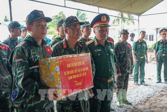 Thượng tướng Lê Quang Minh tặng quà cho Đội tìm kiếm, quy tập hài cốt liệt sĩ (lâm thời) thành phố Cần Thơ đang làm nhiệm vụ tìm kiếm hài cốt liệt sĩ tại ấp Trường Hòa, xã Thới Lai. Ảnh: Thanh Liêm - TTXVN