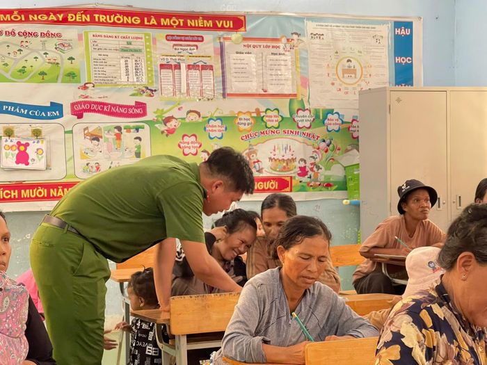 "Thầy giáo" mặc sắc phục Công an hướng dẫn học viên lớp bình dân học vụ tập viết.