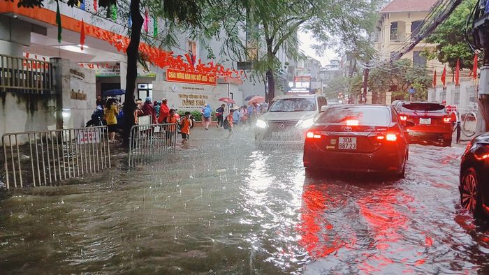 Tại khu vực cổng trường Tiểu học và THCS Đông Thái, mưa lớn và tình trạng úng ngập đã gây khó khăn trong việc tham gia giao thông.
