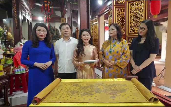 Hiệu trưởng Trường THCS Trần Duy Hưng (ngoài cùng bên trái) cùng lãnh đạo phường Yên Hòa tìm hiểu một trong những đạo sắc phong được lưu giữ tại cụm di tích Đình Trong - Đình Ngoài - Đền Dục Anh. Ảnh: PV