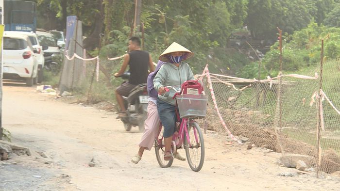 Bà Lê Thị Hà lo lắng khi đưa đón cháu đi học qua khúc đường đang bị sụt lở này. Ảnh: Thái Trọng