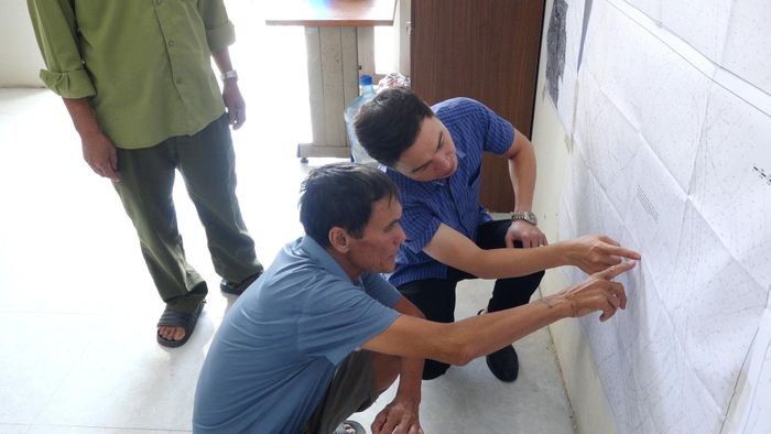 Ông Nguyễn Văn Hải tìm hiểu vị trí nhà, đất của gia đình trên bản đồ quy hoạch và trao đổi những vấn đề còn băn khoăn. Ảnh: Đỗ Duẩn