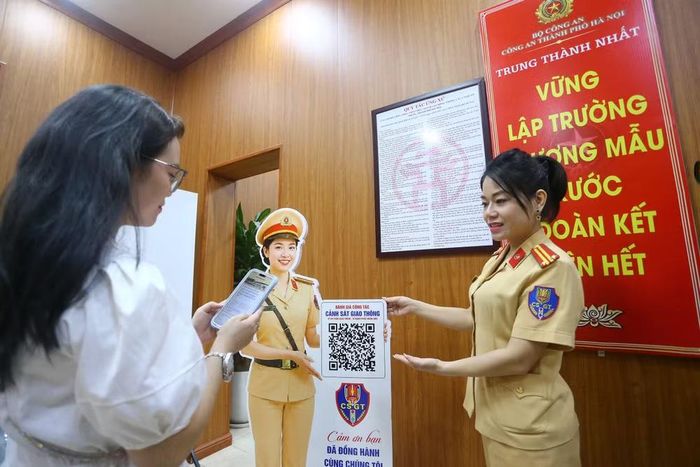 Cán bộ Cảnh sát giao thông hướng dẫn người dân quét mã QR để đánh giá chất lượng phục vụ và đóng góp ý kiến. Việc đẩy mạnh ứng dụng công nghệ và công khai đánh giá thể hiện tinh thần cầu thị, không ngừng đổi mới để phục vụ nhân dân ngày càng tốt hơn