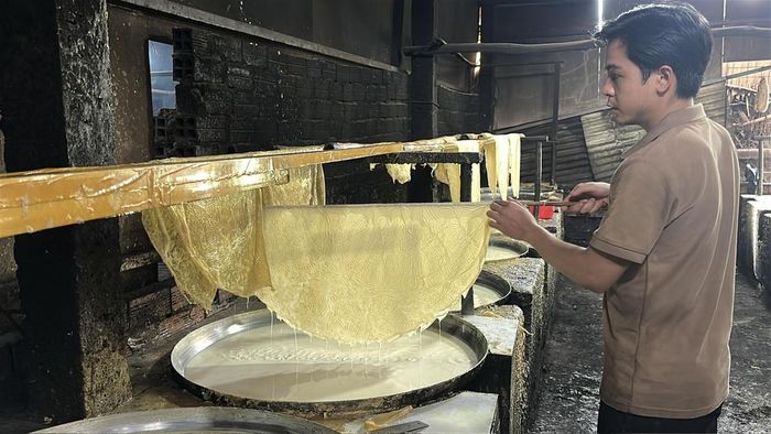 Anh Hà Trung Hiếu khéo léo vớt lớp váng đậu, công đoạn đòi hỏi người thợ phải có kinh nghiệm. (Ảnh: Thanh Lâm).