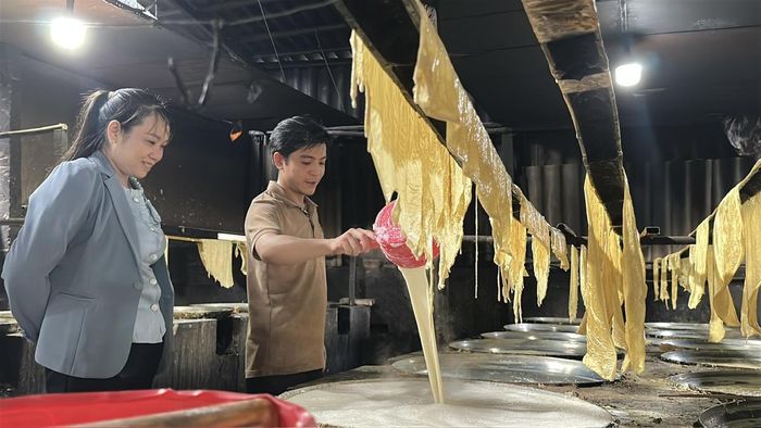 Anh Hà Trung Hiếu, người thợ trẻ của làng nghề, giới thiệu quy trình làm tàu hũ ky với bà Nguyễn Thị Ánh Loan, cán bộ Phòng Kinh tế phường Cái Vồn. (Ảnh: Thanh Lâm).