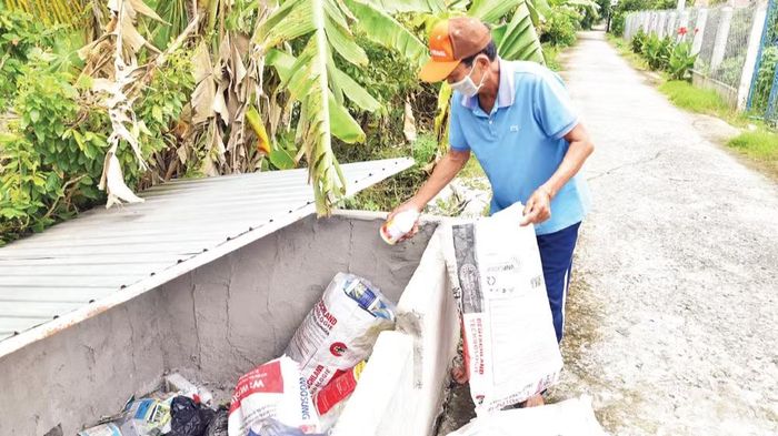 Ông Nguyễn Văn Bé, ấp 3, xã Mỹ Thành, tỉnh Đồng Tháp phân loại và cho bao gói vào hố chứa đúng quy định.