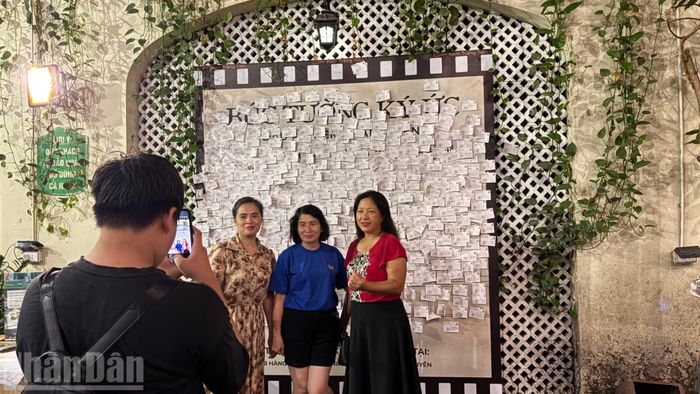 Nhiều người tranh thủ chụp ảnh bên bức tường lưu lại những dòng thư gửi về cửa hàng kem Tràng Tiền để làm kỷ niệm trước khi cơ sở chuyển sang địa điểm mới.