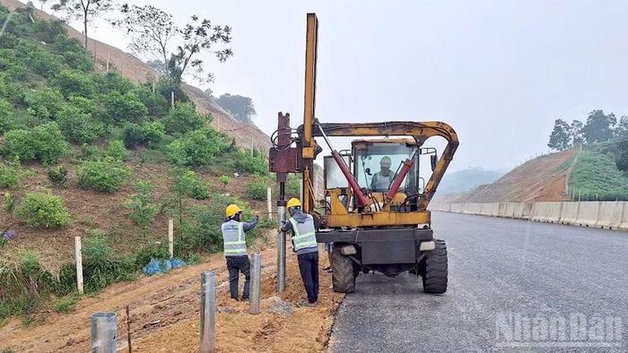 Công ty trách nhiệm hữu hạn xây dựng Tự Lập huy động máy và nhân công lắp đặt lan can trên tuyến. (Ảnh: Đức Thắng)
