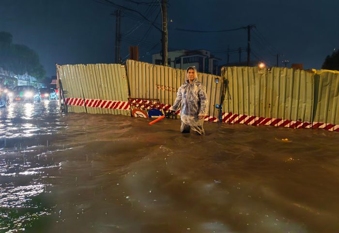  Một số người dân sống gần đường Bà Triệu đã ra phân luồng, hướng dẫn phương tiện tránh vào chỗ nước sâu. Ảnh: NGUYỄN TÂN 