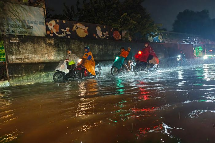  Nhiều người dân phải đi lên vỉa hè để tránh nước ngập. Ảnh: NGUYỄN TÂN 