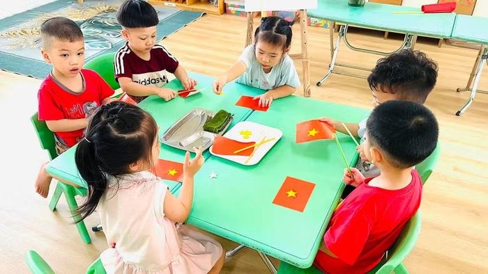 Trẻ tập dán lá cờ Tổ quốc tại Trường Mầm non Ngô Thì Nhậm, phường Hà Đông, Hà Nội. Ảnh: Đình Tuệ.