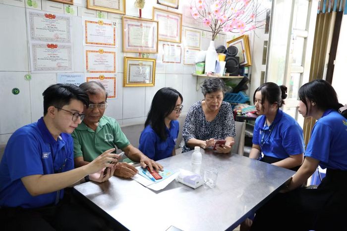 Sinh viên Trường Đại học Sư phạm TPHCM giúp các cán bộ khu phố sử dụng ứng dụng Sổ tay đảng viên điện tử. Ảnh: Ngô Tùng