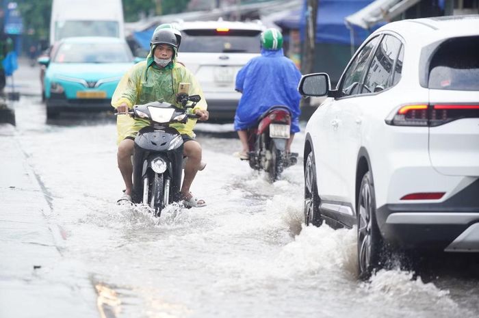Ô tô di chuyển chậm qua đoạn ngập trên đường Chiến Thắng, khu vực gần chợ Triều Khúc.