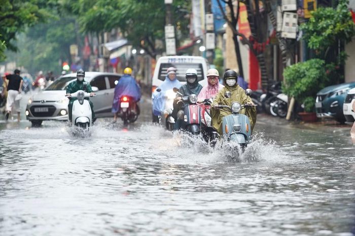 Phố Hoàng Văn Thái ngập sâu, các phương tiện di chuyển chậm qua khu vực ngập.