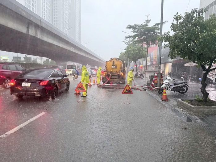 Công nhân thoát nước túc trực mở nắp hố ga, vớt rác để nước rút nhanh sau cơn mưa dông chiều 10/9.