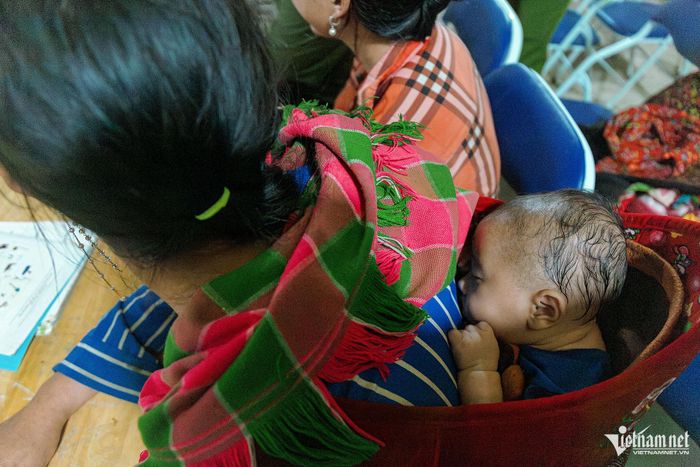 Cháu Vàng Minh Quân ngủ say trên lưng mẹ. Cháu theo mẹ đến lớp khi vượt qua quãng đường rừng hơn 4 km.