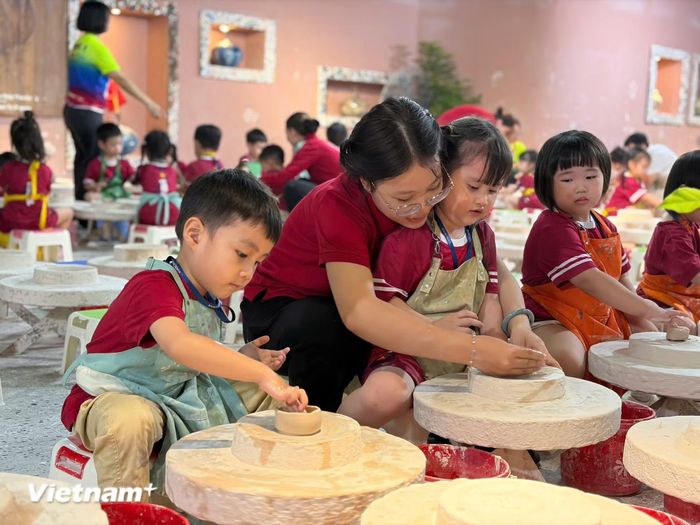 Các du khách nhí trải nghiệm làm gốm ở Bát Tràng. (Ảnh: CTV/Vietnam+)