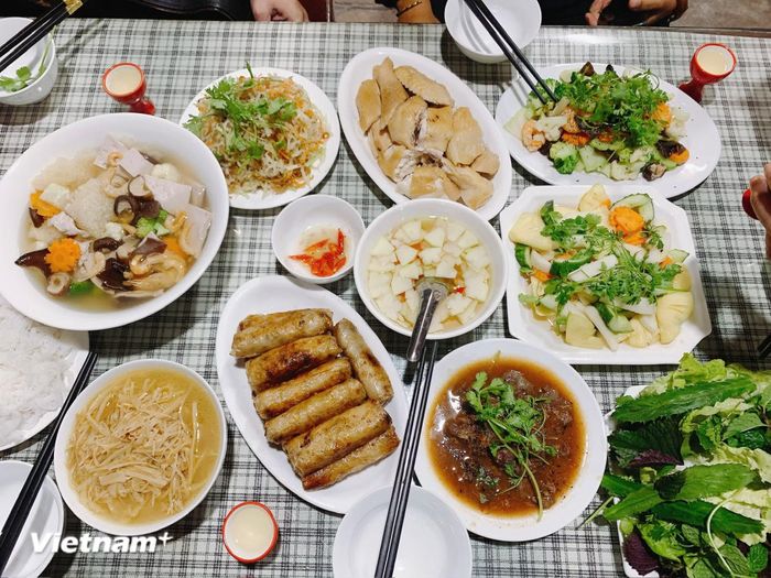 Du khách quốc tế tham quan nhà cổ ở Bát Tràng và thưởng thức mâm cỗ truyền thống do nghệ nhân của làng chế biến. (Ảnh: Xuân Mai/Vietnam+)