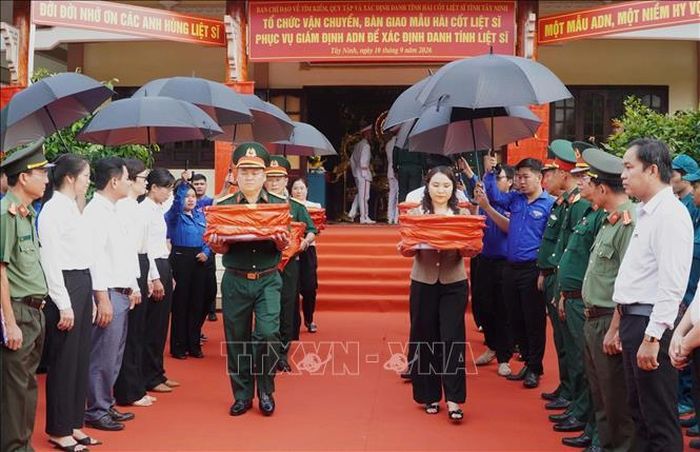 Đại biểu cẩn trọng đưa những hộp mẫu sinh phẩm hài cốt liệt sĩ lên xe chuyên dụng. Ảnh: TTXVN phát