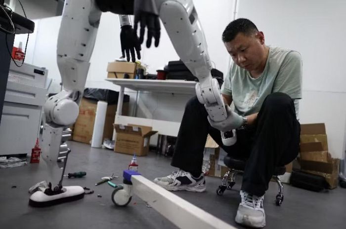 Một kỹ sư đang làm việc trên chân của robot hình người Tiangong Omni tại khu vực nghiên cứu và thử nghiệm của Trung tâm Đổi mới Robot Hình người Bắc Kinh. Ảnh: Reuters.