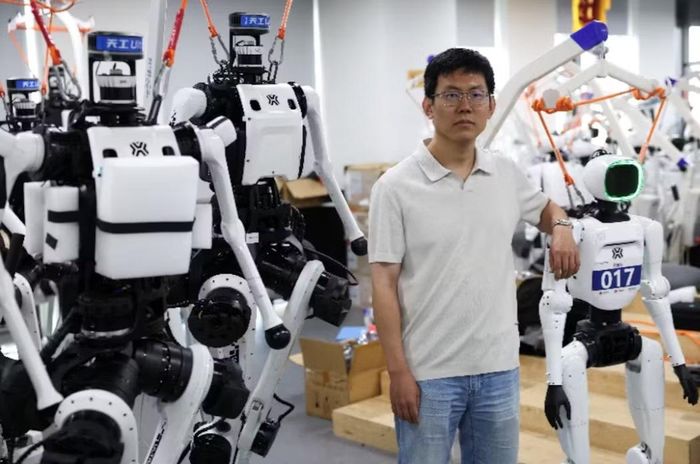 Jack Guo, kỹ sư dẫn đầu việc phát triển Tiangong Ultra, đứng giữa các robot hình người Tiangong Ultra và Tiangong Omni khi anh chụp ảnh tại Trung tâm Đổi mới Robot Hình người Bắc Kinh, hay còn gọi là X-Humanoid, ở Bắc Kinh, Trung Quốc, ngày 4/9. Ảnh: Reuters.