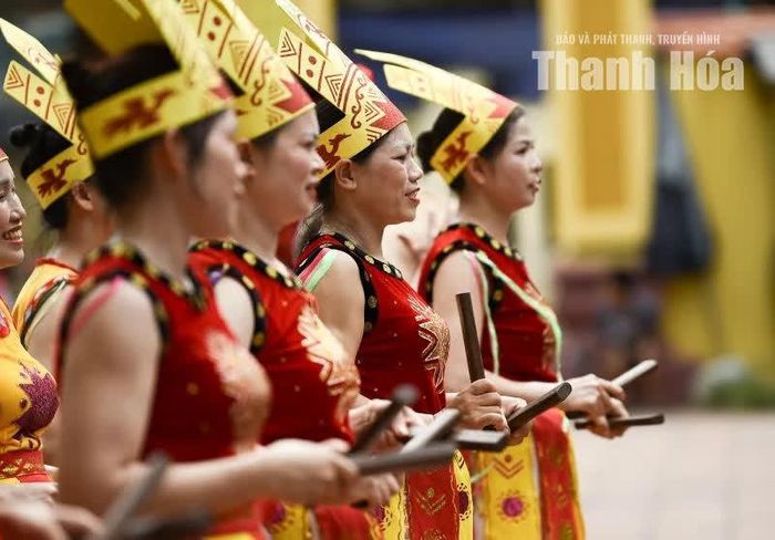 Hai tay cầm hai thanh sênh gỗ, người biểu diễn vừa đi vừa gõ vào nhau thành tiếng lách cách vui tai.