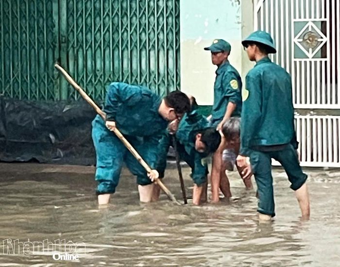 Lực lượng Dân quân phường được điều động tới khu vực ngập sâu trên Tỉnh lộ 9 để khơi thông nắp cống thoát nước.