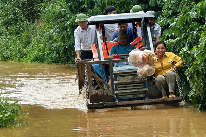 Lực lượng chức năng hỗ trợ người dân di chuyển qua vùng ngập xã Quảng Hòa