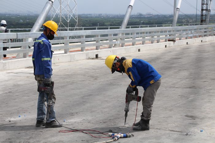 Anh Nguyễn Văn Tư (phải) chia sẻ, thời điểm mới đến công trình, nhiều hạng mục vẫn còn dang dở mà nay gần về đích. “Mới đó đã hơn một năm anh em cùng ăn ngủ, bám trụ để hoàn thiện phần còn lại của cây cầu. Giờ cầu nối liền đôi bờ, uốn lượn vắt qua sông Lòng Tàu, hiện đại và đẹp. Ai cũng cố gắng đẩy nhanh công việc để sớm được chứng kiến những dòng xe qua cầu”, anh Tư nói.